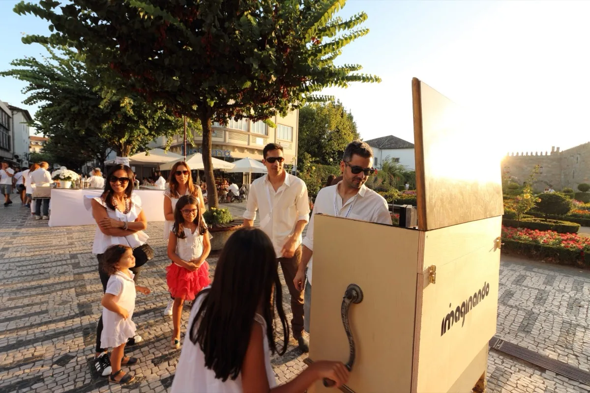 夕暮れの Braga の広場で Digital Music Box を囲む家族連れ。子どもたちが 代わる代わるクランクを回している。